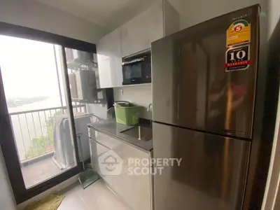 Modern compact kitchen with stainless steel appliances and balcony view