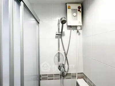 Modern bathroom with sleek shower and water heater in a tiled setting.