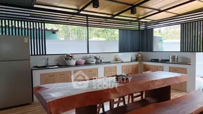 Spacious open-layout kitchen with modern appliances and wooden dining table, perfect for culinary enthusiasts.