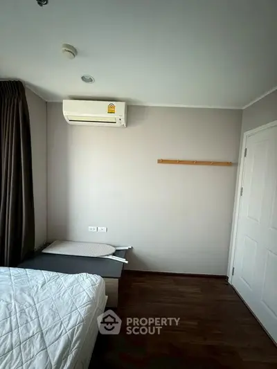 Cozy bedroom with air conditioning and wooden flooring, ideal for comfortable living.