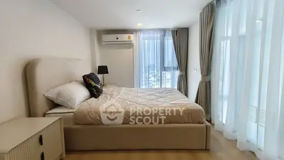 Spacious bedroom with modern decor and large windows offering natural light.