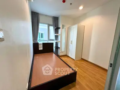 Compact bedroom with wooden flooring and modern furnishings in a cozy apartment.