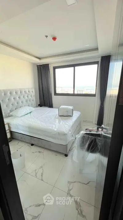 Modern bedroom with large window and elegant furnishings in a high-rise apartment.