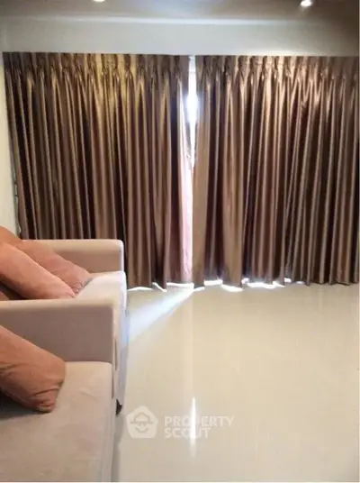 Spacious living room with elegant curtains and plush seating, perfect for relaxation.