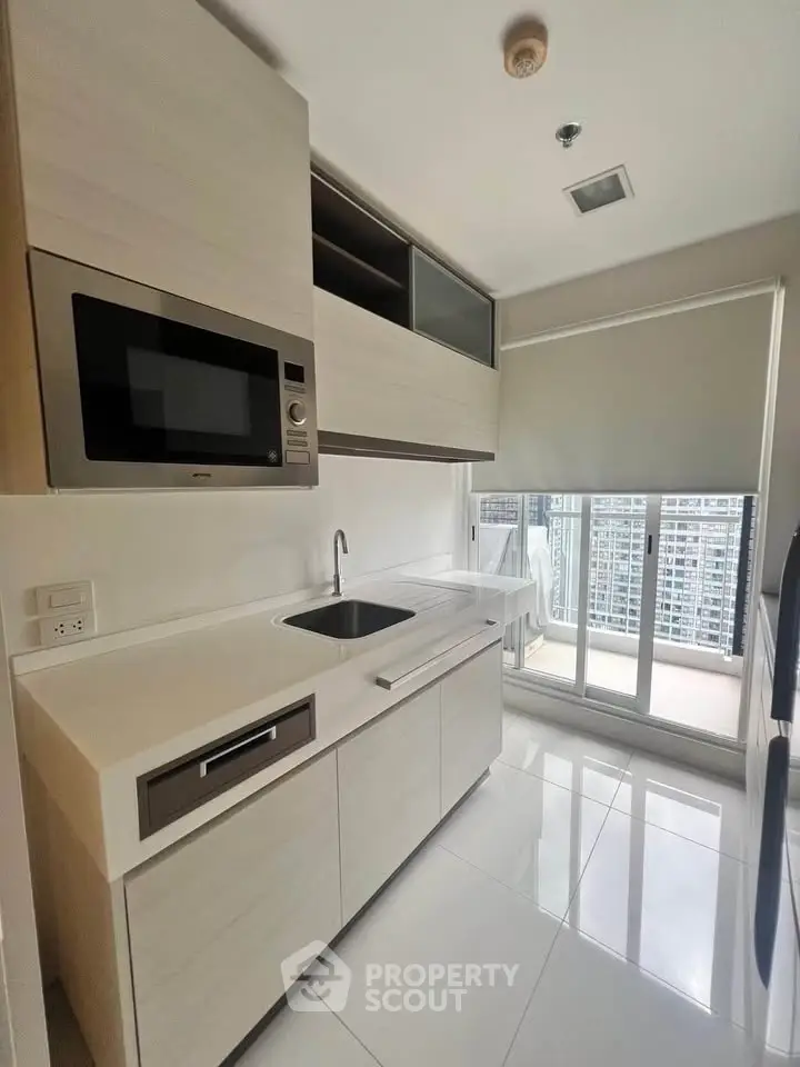 Modern kitchen with sleek cabinetry and balcony view in high-rise apartment.
