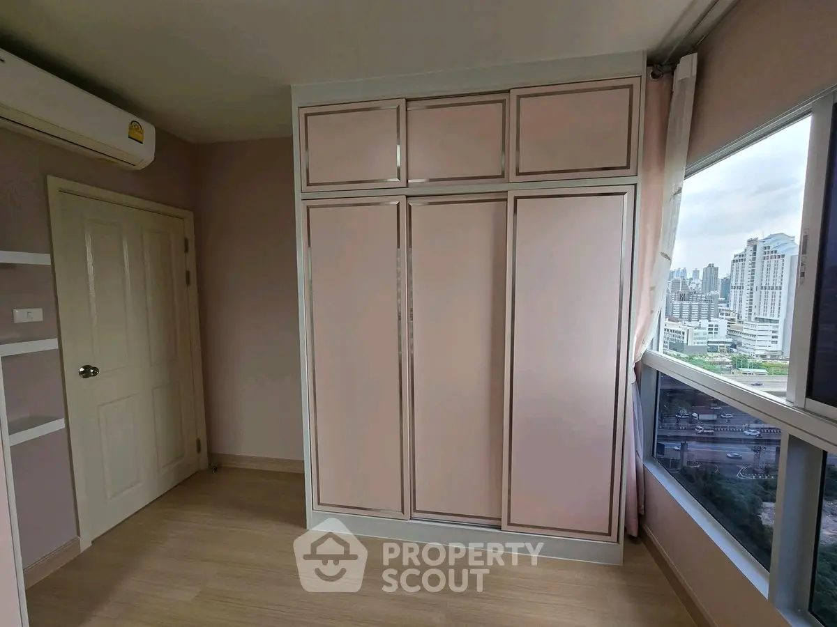 Spacious bedroom with built-in wardrobe and city view in modern apartment