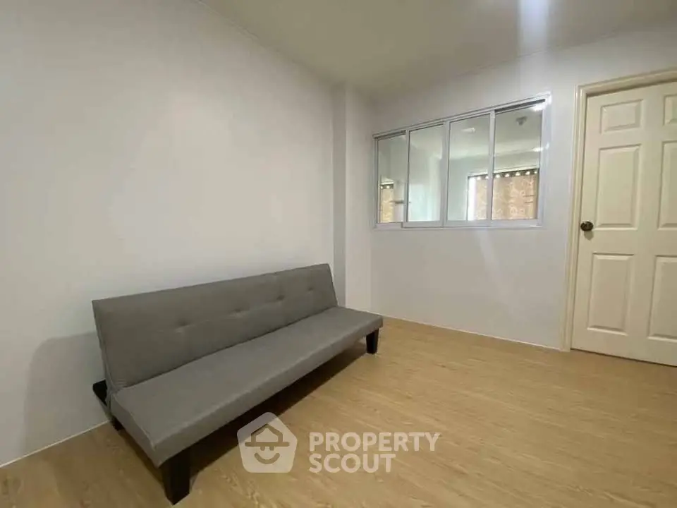 Minimalist room with gray sofa and wooden flooring, perfect for modern living.