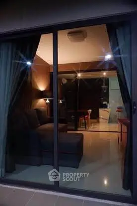 Cozy living room with modern decor and ambient lighting viewed through glass doors.