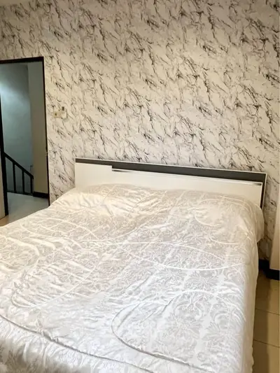 Spacious bedroom with elegant marble-patterned wallpaper and cozy bedding.