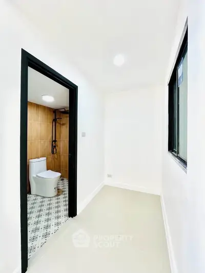 Bright hallway leading to a modern bathroom with stylish tile flooring.