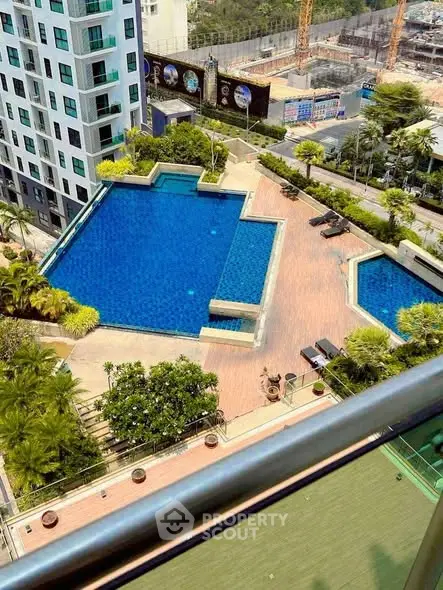 Stunning aerial view of modern apartment complex with luxurious swimming pool and lush greenery.
