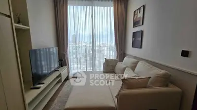 Modern living room with large window and city view, featuring a cozy sofa and sleek TV setup.