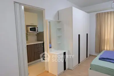 Modern bedroom with adjacent kitchen featuring sleek cabinetry and cozy decor.