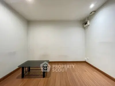 Minimalist room with wooden flooring and a small black table, ideal for cozy living space.