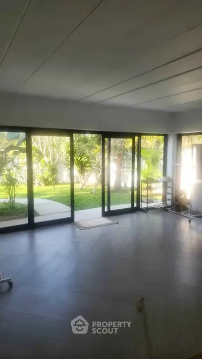 Spacious living room with large glass doors opening to a lush garden view, perfect for indoor-outdoor living.