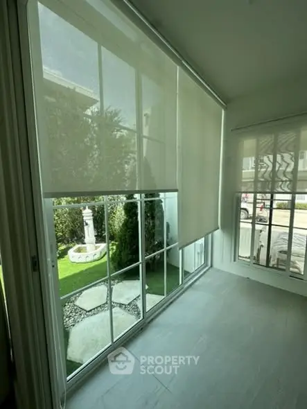 Bright sunroom with large windows overlooking a landscaped garden.