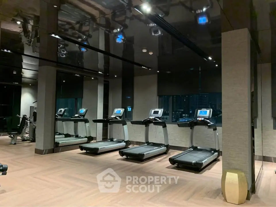 Modern gym with multiple treadmills and sleek interior design in luxury building.