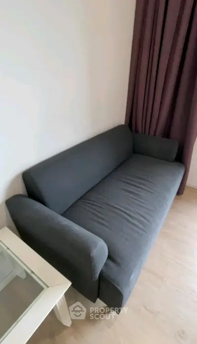Modern gray sofa in a cozy living room with elegant curtains and a stylish side table.