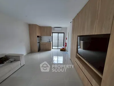 Modern open-plan living room with sleek kitchen and large TV unit