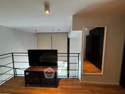 Modern loft with sleek design and large mirror, featuring a stylish TV setup and wooden flooring.