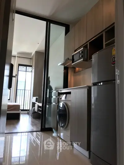 Modern kitchen with sleek appliances and open layout leading to living area.