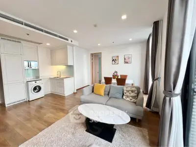Spacious modern living room with open kitchen and dining area, featuring elegant decor and natural light.