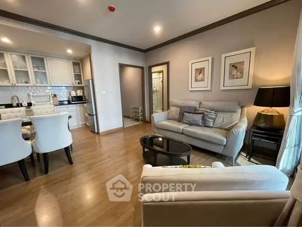 Elegant living room with modern kitchen in open layout, featuring stylish decor and cozy seating.