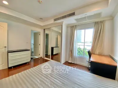 Spacious bedroom with elegant decor and large window offering city views.