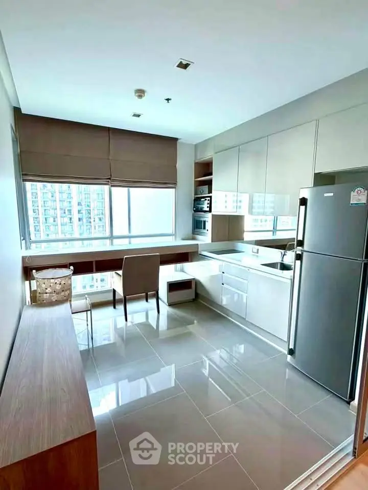 Modern kitchen with sleek cabinetry and stainless steel appliances in high-rise apartment.