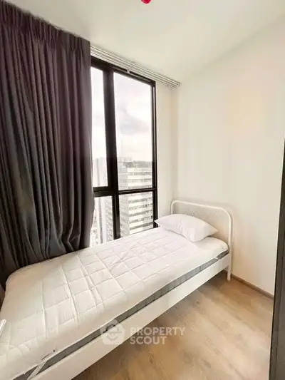 Cozy bedroom with single bed and large window offering city view