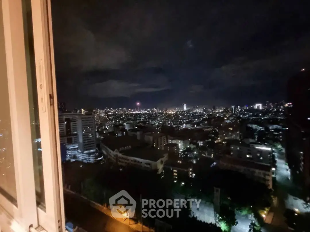 Stunning cityscape night view from high-rise apartment window, showcasing vibrant urban lights.