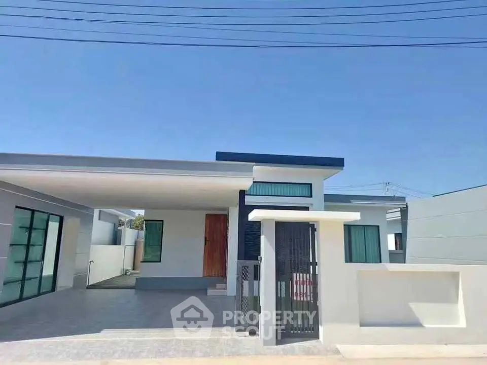 Modern single-story house with sleek design and spacious driveway under clear blue sky.