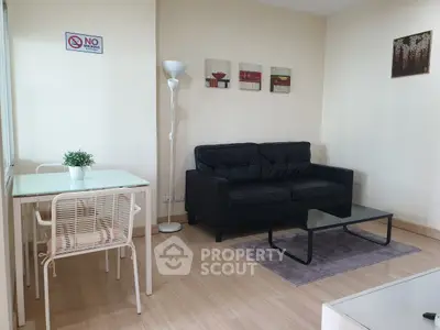 Modern living room with black sofa, glass coffee table, and dining area in stylish apartment.