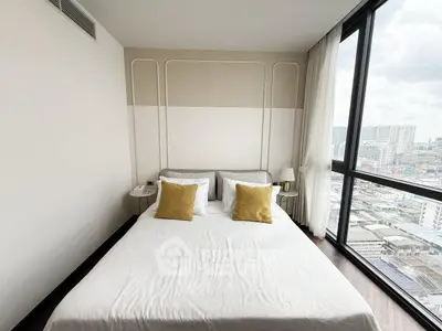 Modern bedroom with large windows offering city views, featuring a cozy bed with stylish decor.