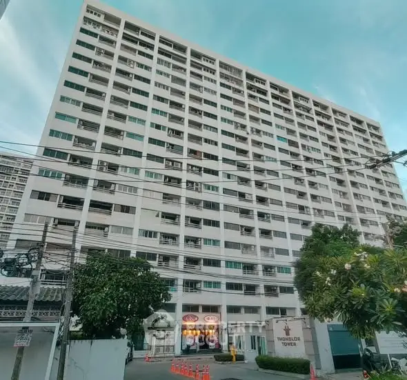 High-rise residential building exterior with lush greenery and clear sky