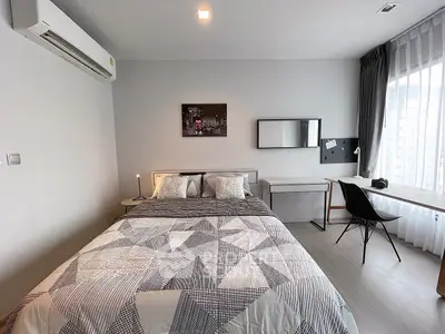 Modern bedroom with stylish decor, large window, and workspace, perfect for urban living.