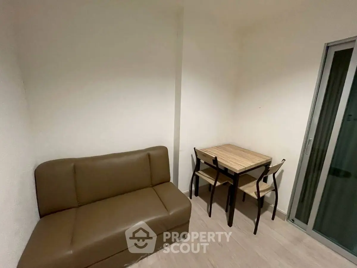 Cozy small living area with brown sofa and compact dining table for two.