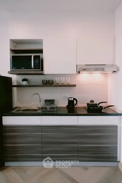Modern kitchen with sleek cabinetry, built-in microwave, and stylish backsplash in a contemporary apartment.