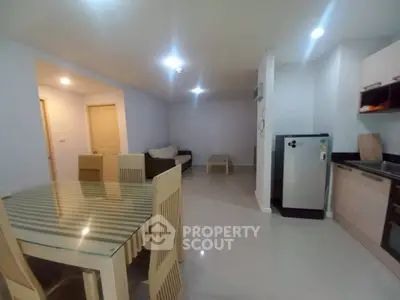 Spacious open-plan living and dining area with modern kitchen in a cozy apartment.