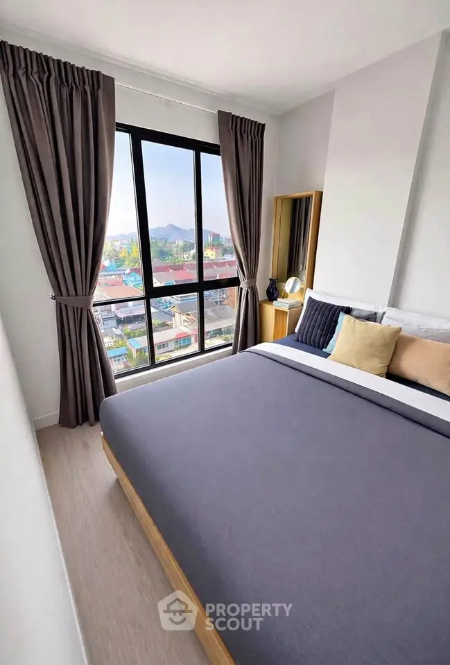 Modern bedroom with large window offering stunning city view, featuring elegant decor and cozy bedding.