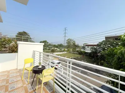 Charming balcony with seating offering serene garden views in a modern residential area.
