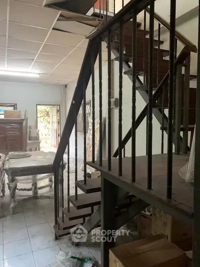 Spacious interior with wooden staircase and tiled flooring, ideal for renovation.