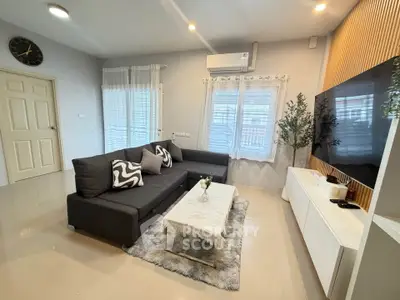 Modern living room with sleek furniture and stylish decor, featuring a large TV and cozy seating area.