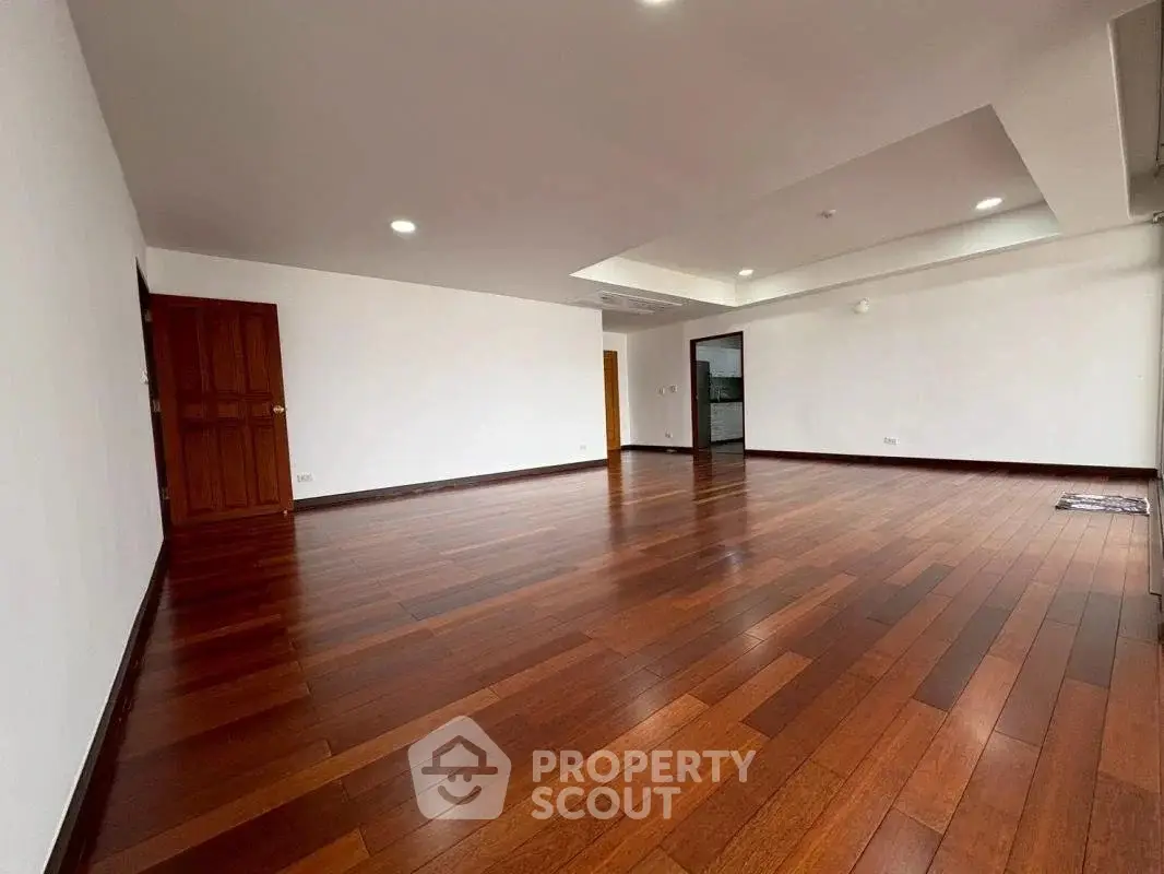 Spacious living room with elegant wooden flooring and modern recessed lighting.