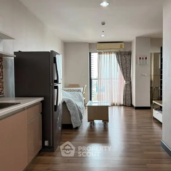 Modern open-plan studio apartment with sleek kitchen and cozy living area.