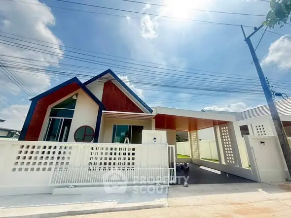 Modern single-story house with unique architectural design and spacious driveway under a clear blue sky.