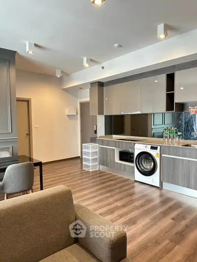 Modern open-plan kitchen with sleek cabinetry and built-in washing machine in stylish apartment.