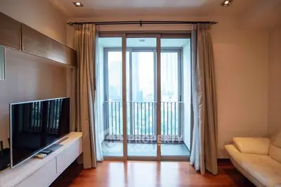 Modern living room with large windows and city view, featuring sleek furniture and wooden flooring.