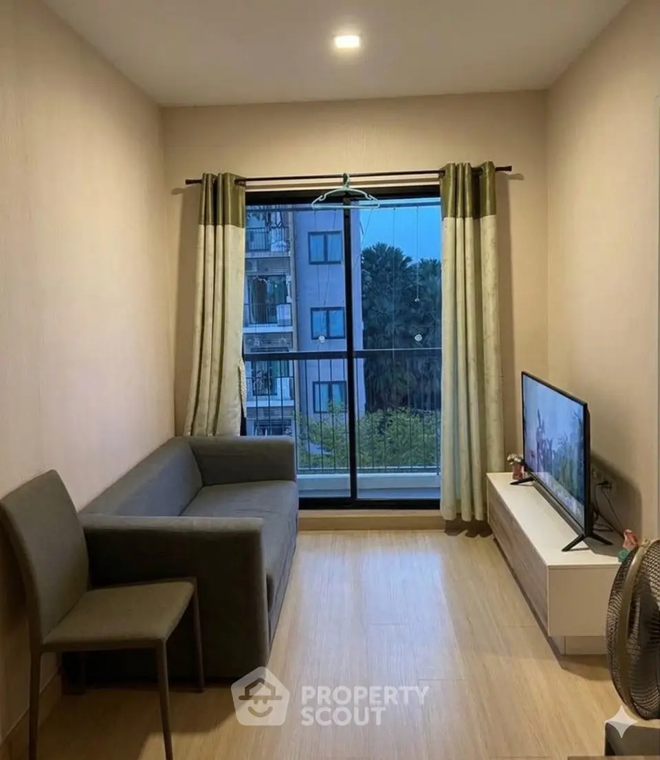 Cozy living room with modern sofa and TV, featuring a large window with a view of the cityscape.
