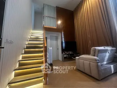 Modern duplex living room with stylish staircase and cozy seating area.